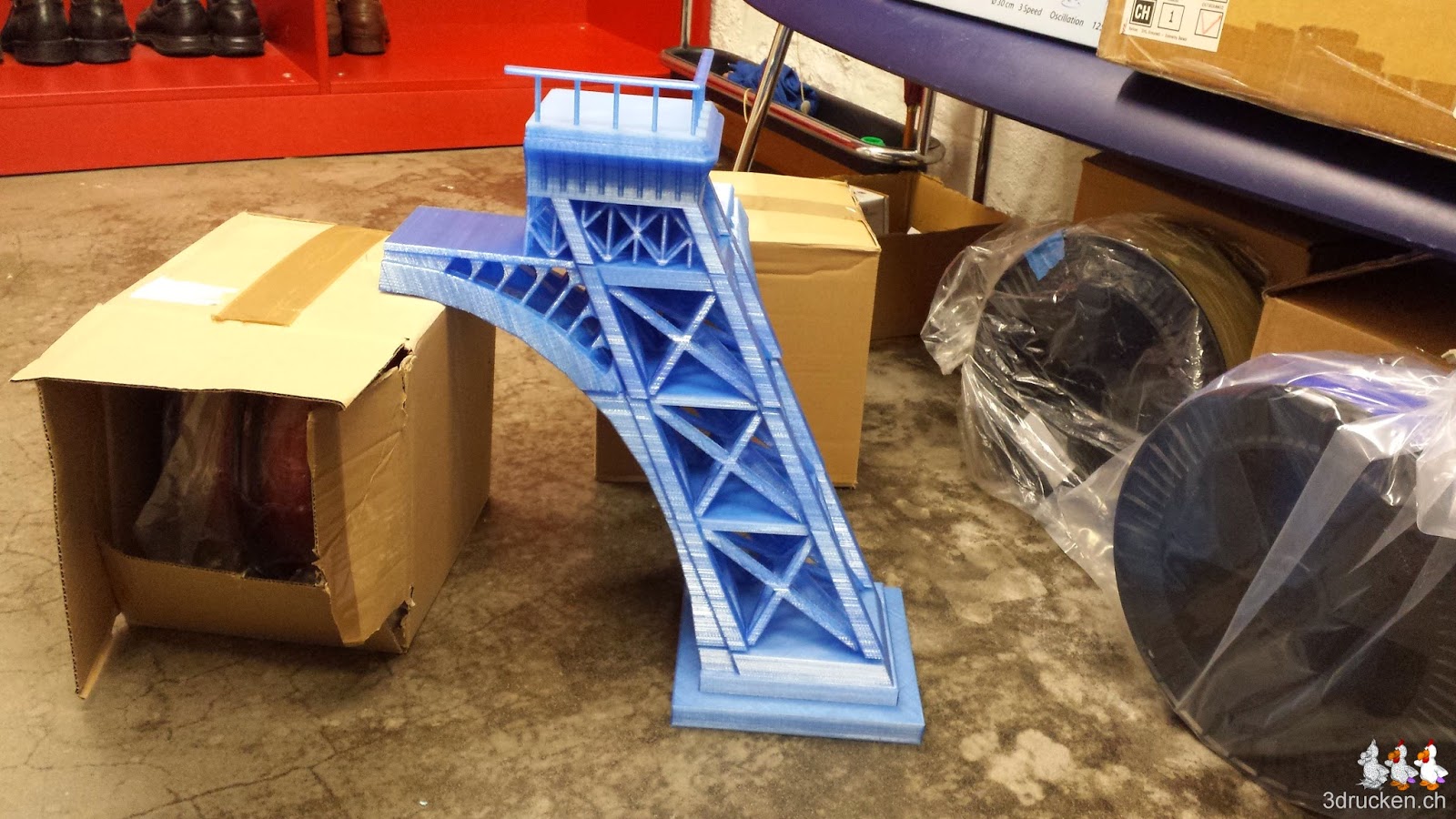 Foto eines provisorisch mit Kartons abgestützten Beins des Eiffelturms